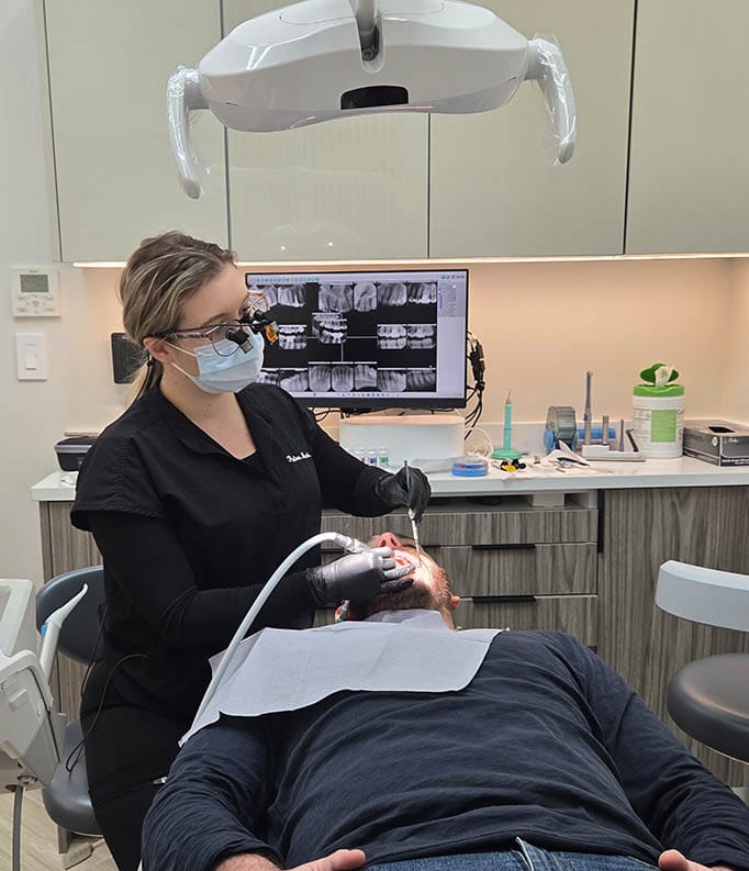 Dentist performing routine family dental exam in modern Brooklyn clinic