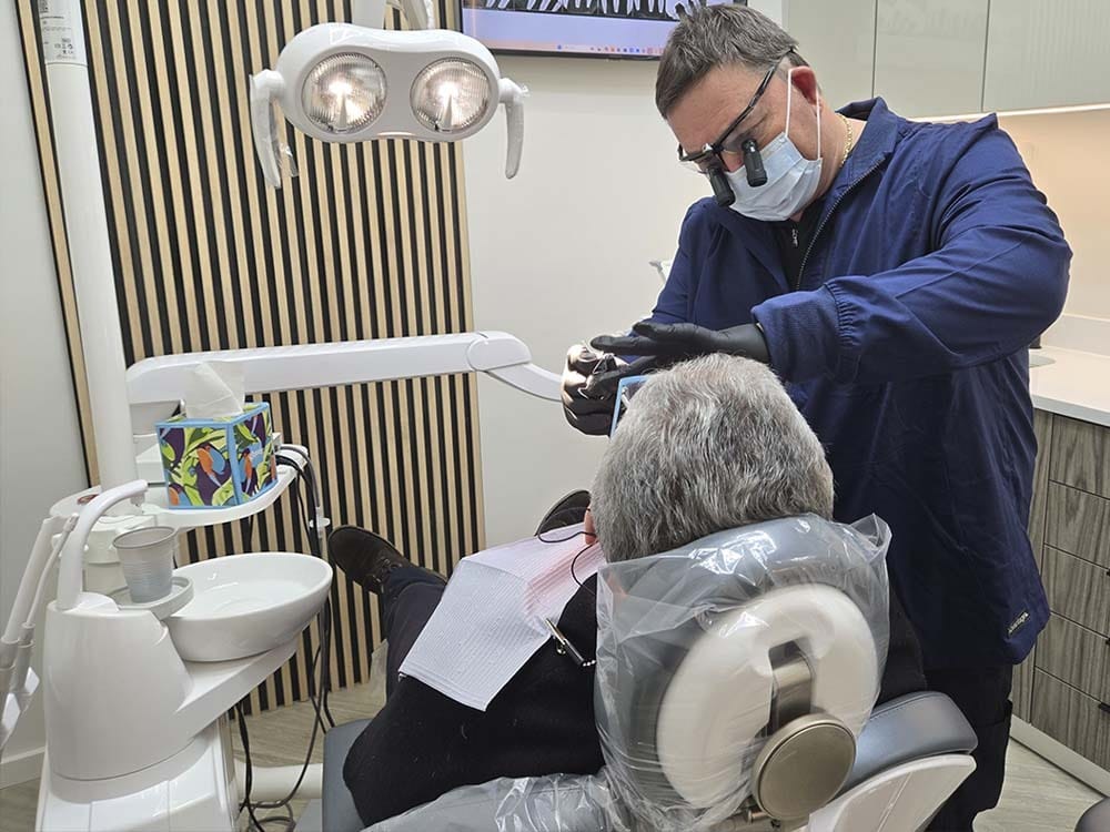 Dentist performing an oral cancer screening examination at VitaDent Brooklyn Dental Group