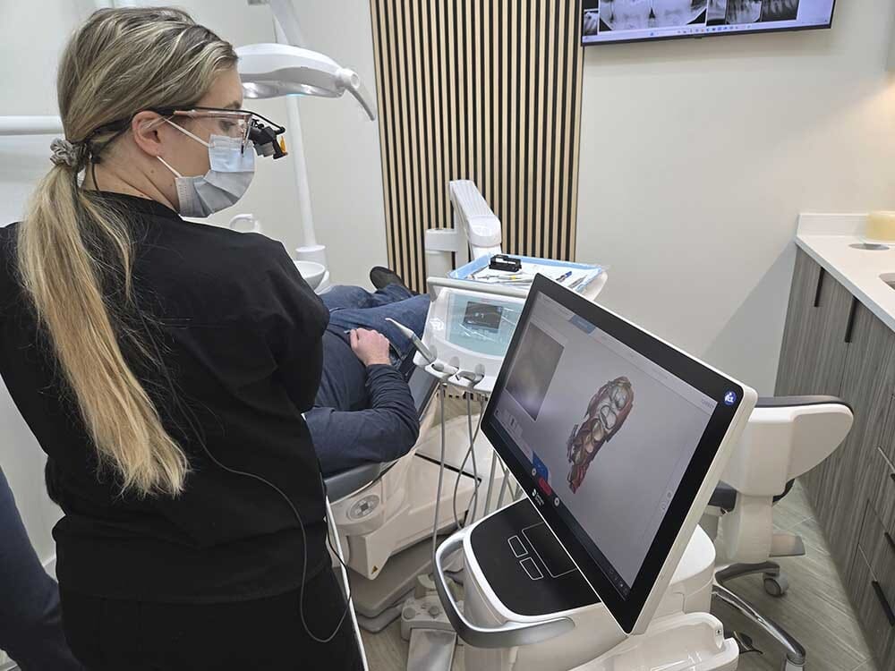 Dentist reviewing oral anatomy on a digital screen during an oral cancer screening evaluation.